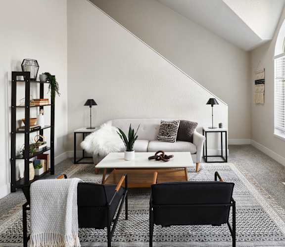 a living room with a white couch and two black chairs